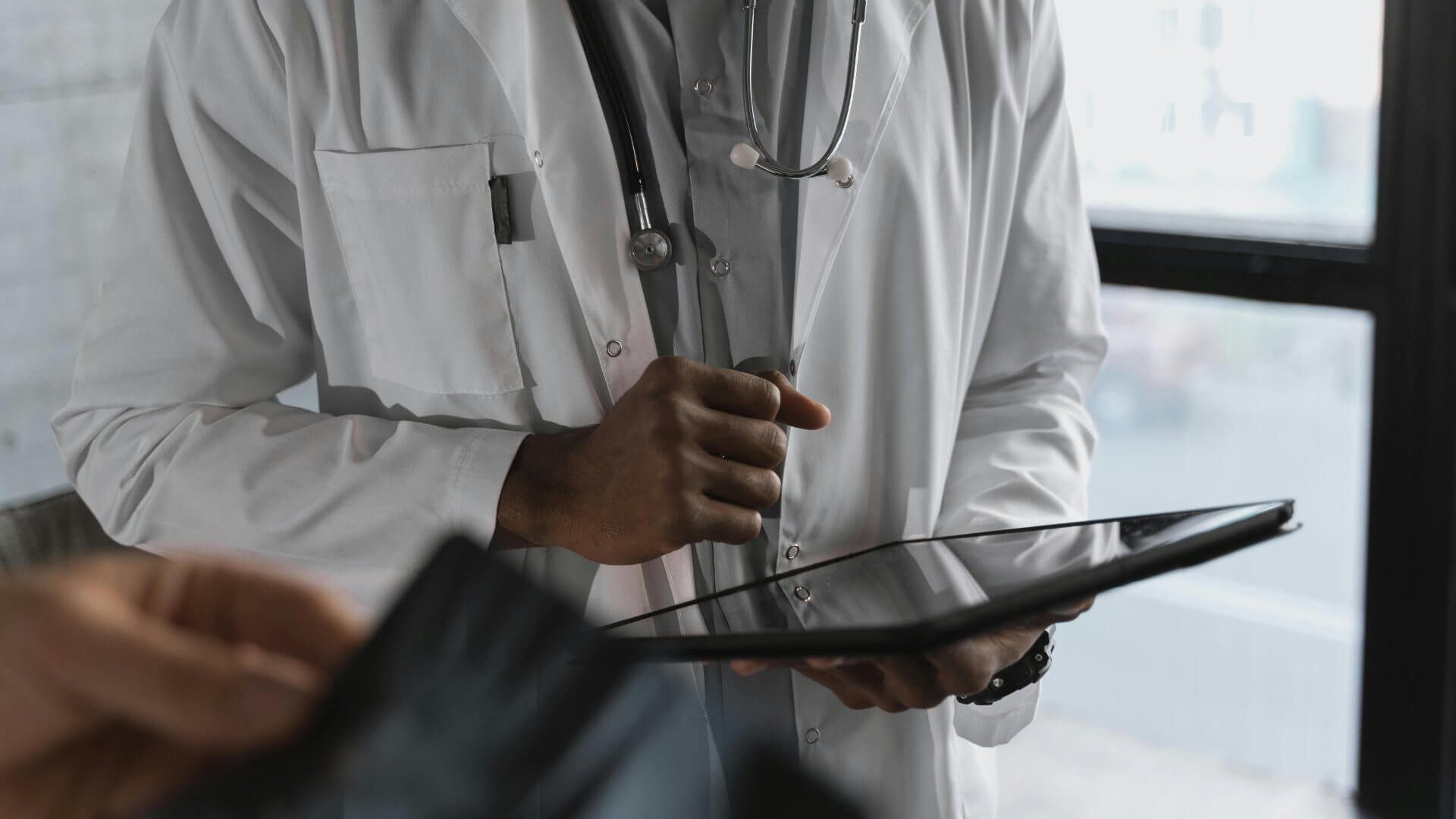 Ärzte in Führungsverantwortung (Startseite) 18 Ärztliche Führungskraft mit Tablet und Stethoskop als Symbol für Verantwortung und bewusste Führung im Gesundheitswesen.