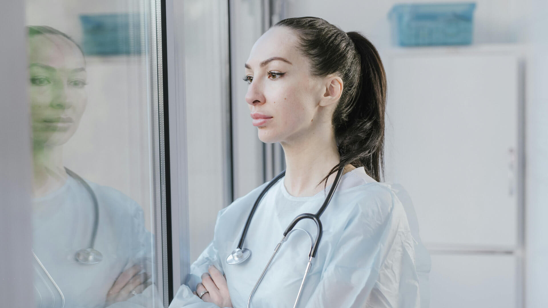 Stabile Führung unter Druck: Was Positive Leadership in Klinik, MVZ und Praxis wirklich leisten kann 3 Ärztin blickt nachdenklich aus dem Fenster als Symbol für Reflexion und Standortbestimmung in der Führung.